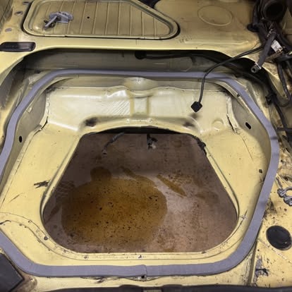 Logement de réservoir mis à nu, corrosion apparente sur la tôle.