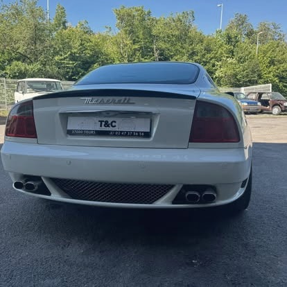Arrière d'un coupé gran turismo blanc, sortie d'atelier.